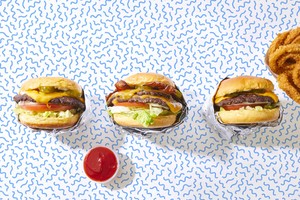 Three burgers and onion rings on a cool wavy blue background